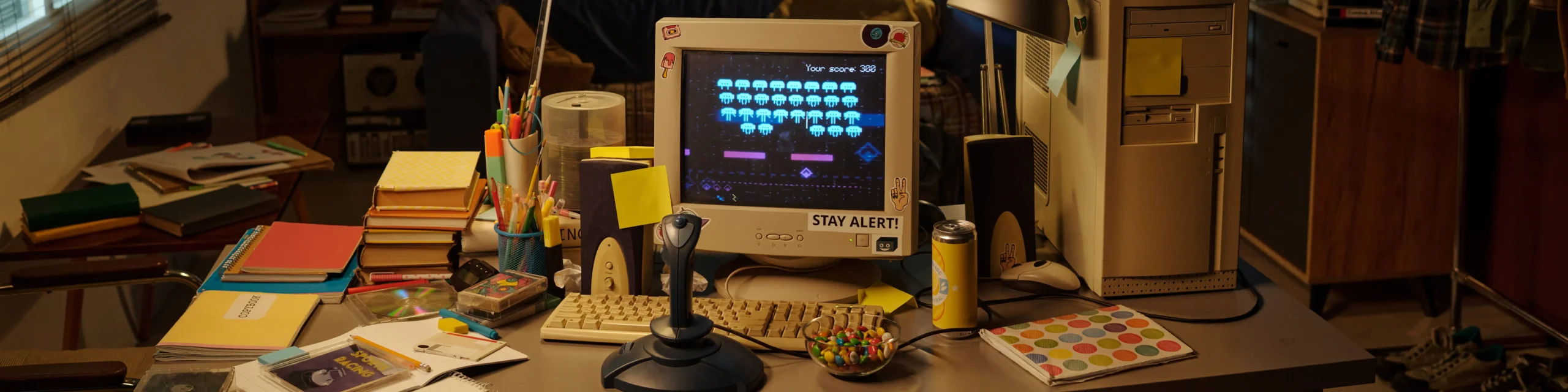 Espacio de trabajo creativo con computador retro y videojuego tipo arcade, representando diseño digital y nostalgia tecnológica